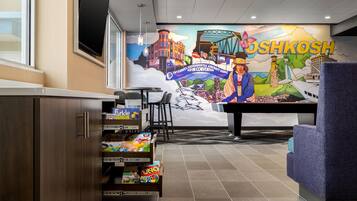Un vestíbulo de hotel con un mural, una recepción y una barra de aperitivos.