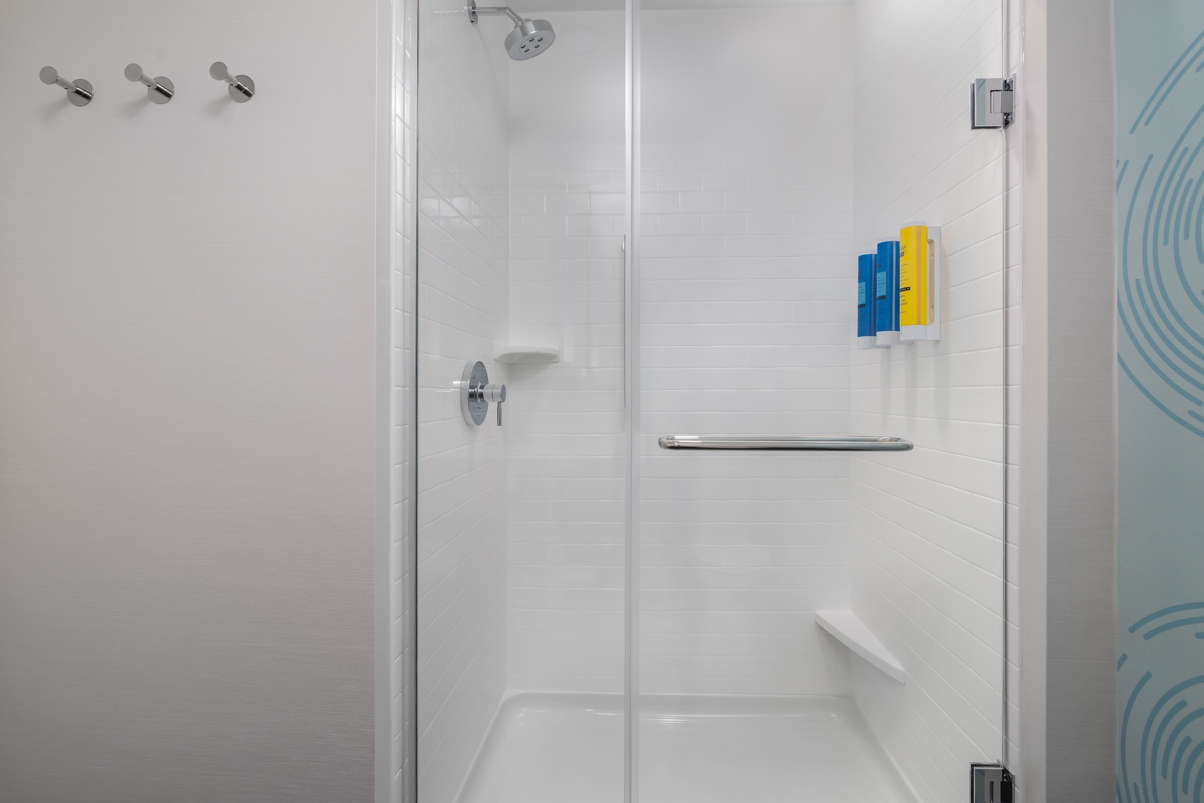 A modern shower with a glass door, a hand dryer, and a towel rack.
