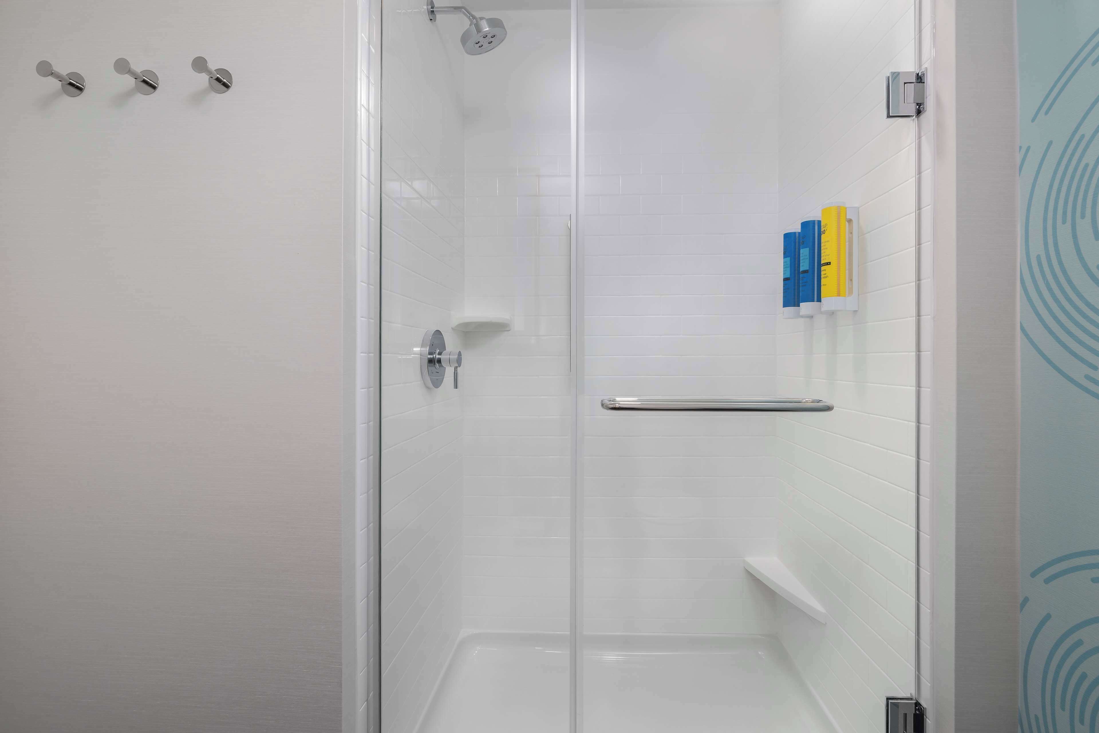 Une douche moderne dotée d’une porte en verre, d’un sèche-mains et d’un porte-serviettes.