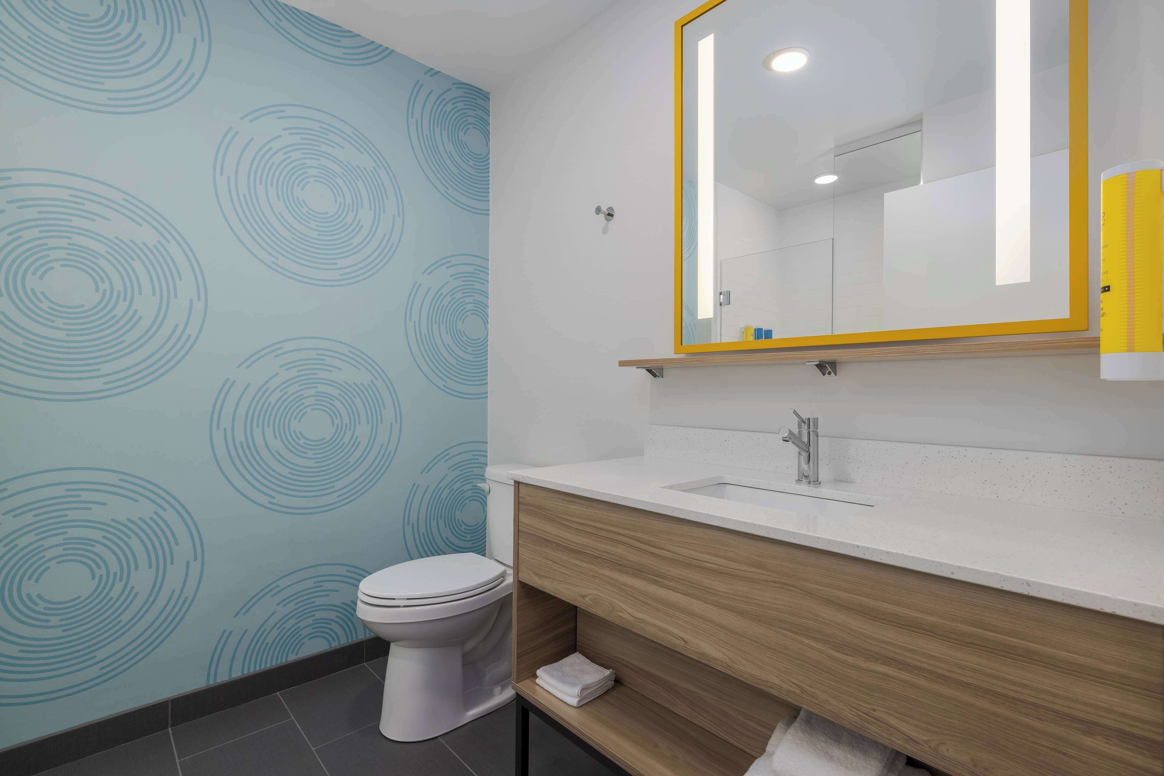A bathroom with a toilet, a sink with a mirror, and a wooden vanity.