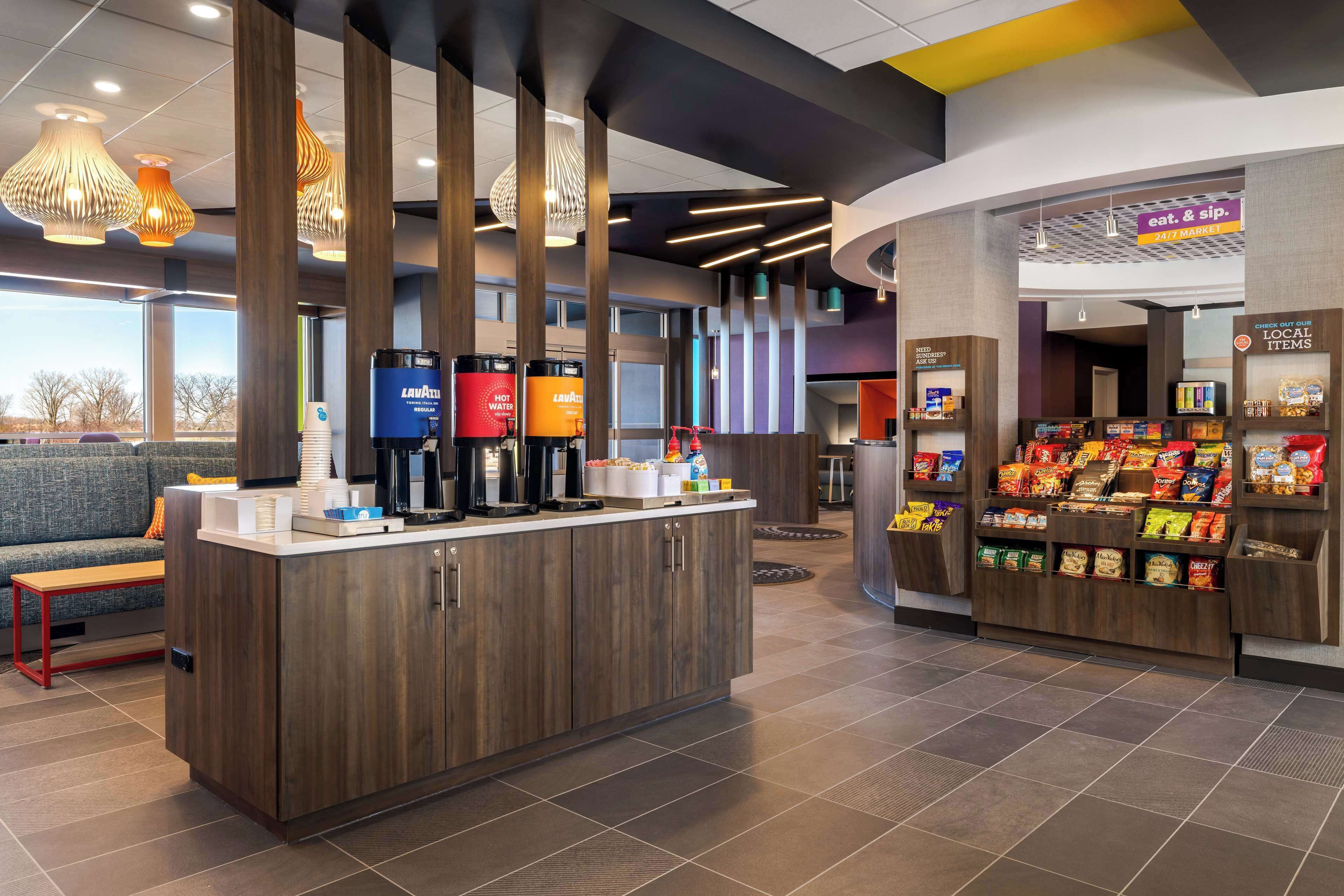 A modern coffee station with a counter, coffee machines, and a snack display.