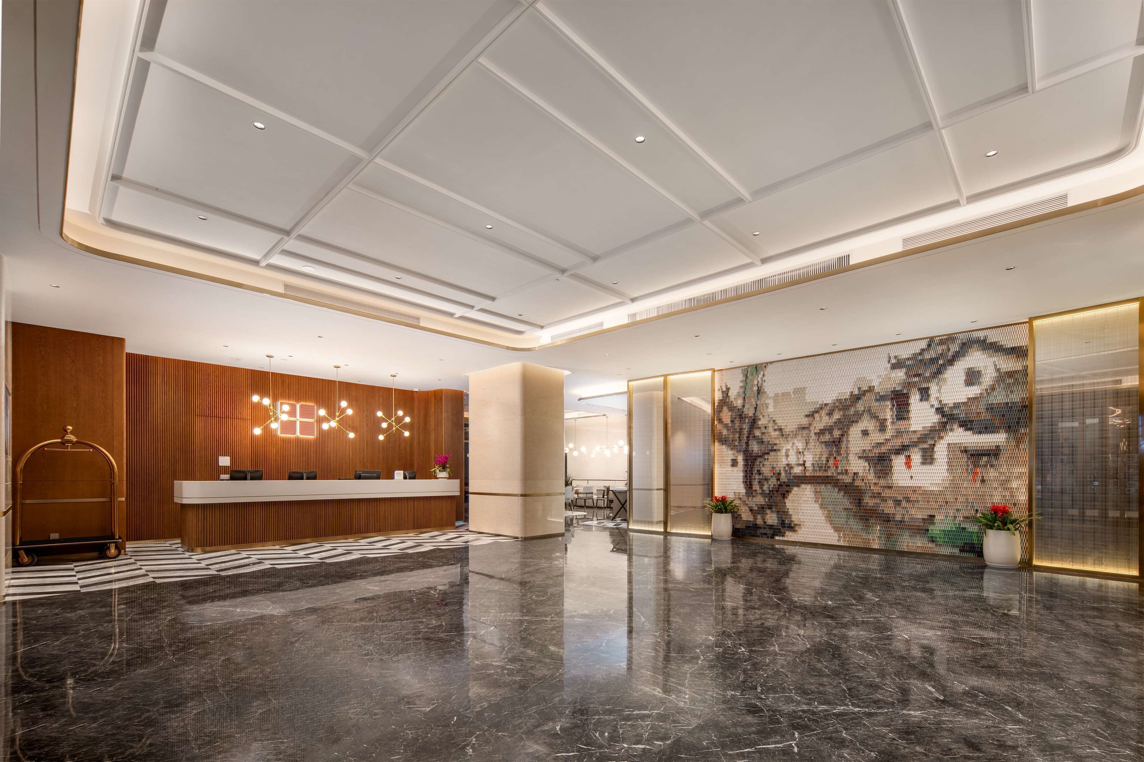 A modern lobby with a reception desk, a large abstract mural, and a polished marble floor.