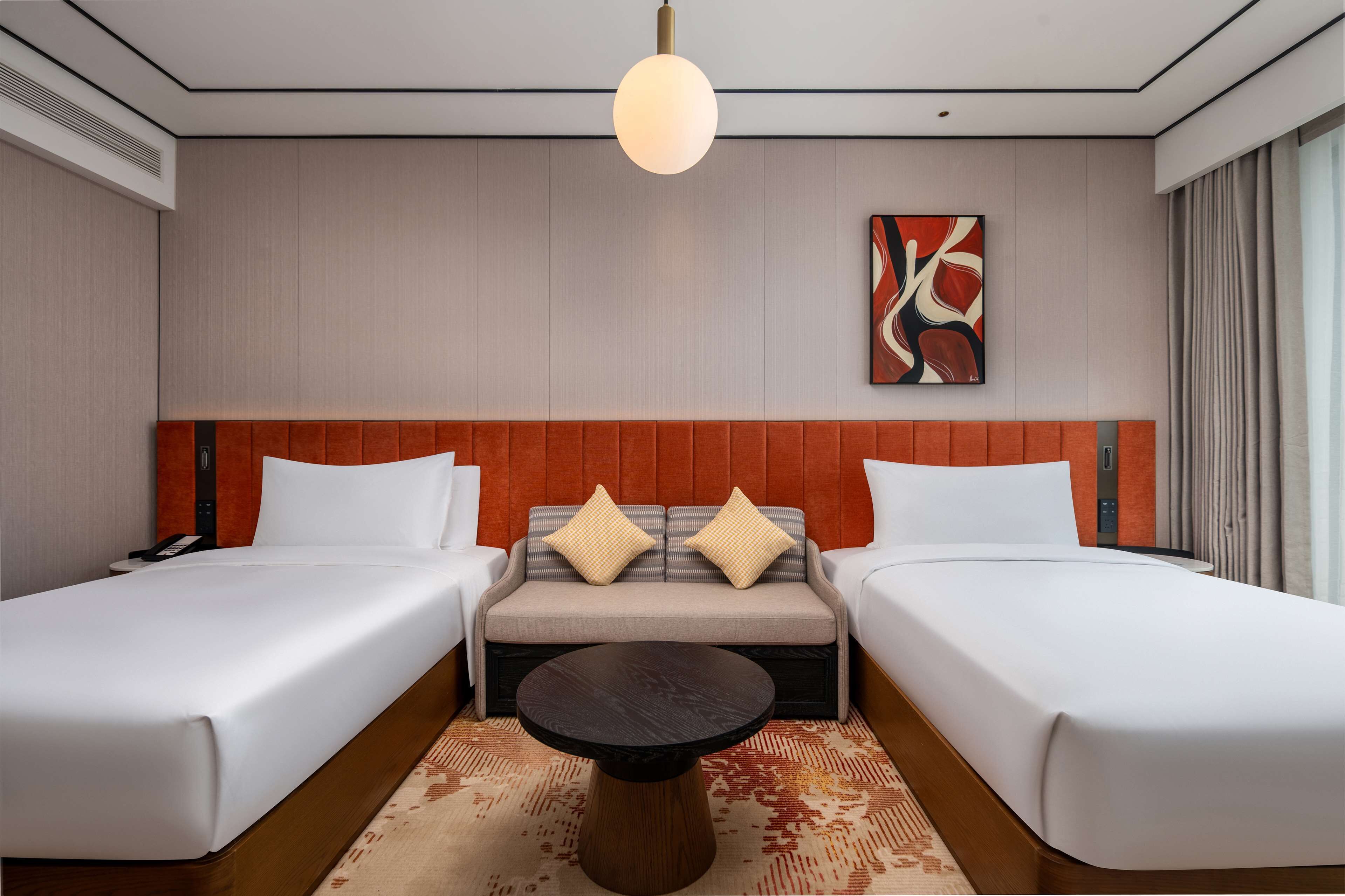 Une chambre d’hôtel avec deux lits, un canapé, une table ronde et un tableau au mur.