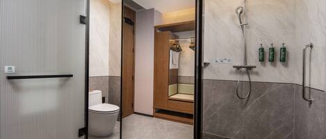 A modern bathroom with a glass partition, a shower, a toilet, and a wooden vanity with a towel rack.