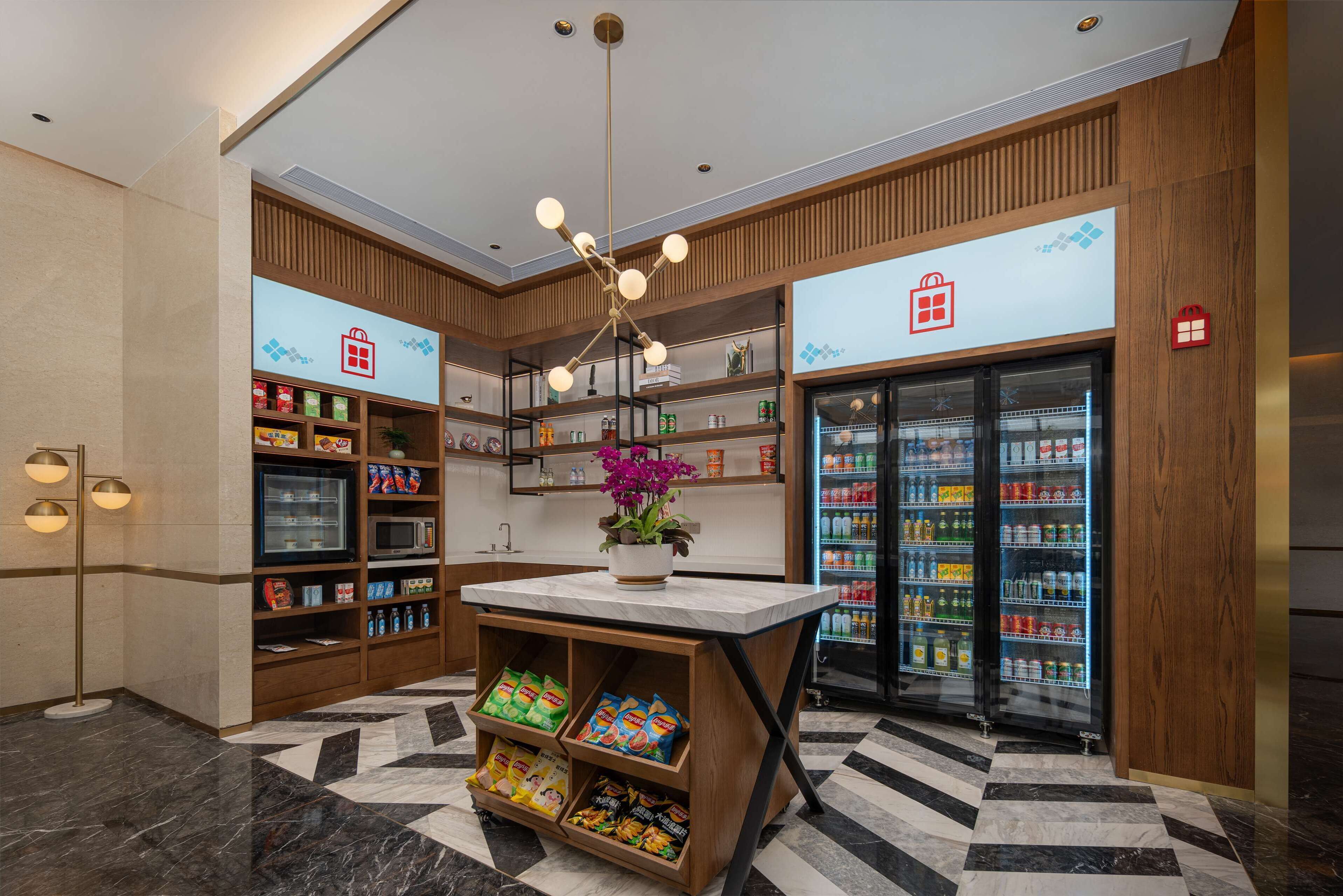 A modern kitchenette with built-in appliances, a central island with seating, and a refrigerator stocked with beverages.