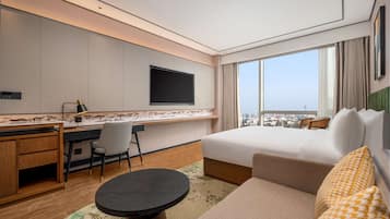 A hotel room with a bed, desk, chair, and a TV mounted on the wall.