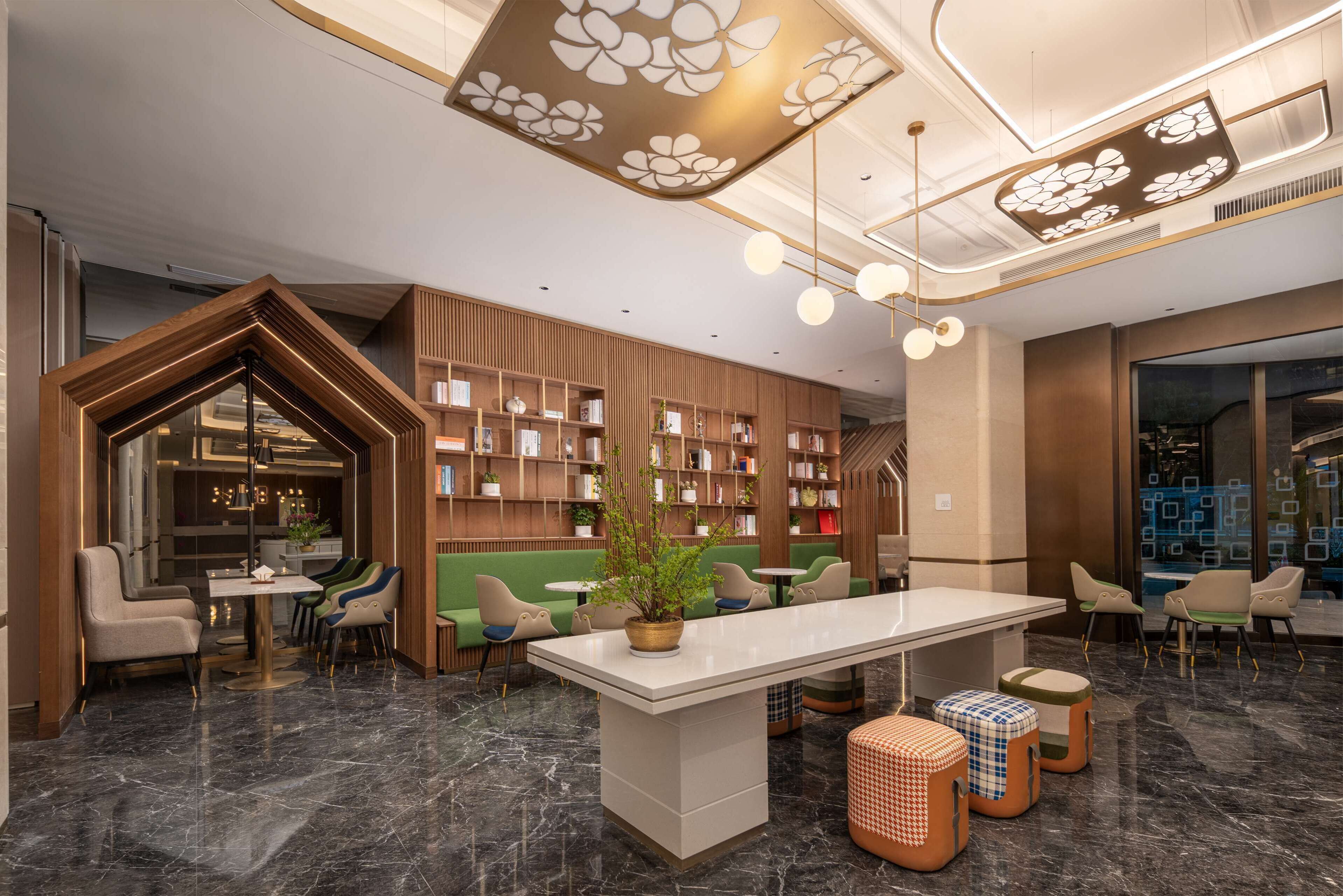 A modern library with a central table, bookshelves, and seating areas.