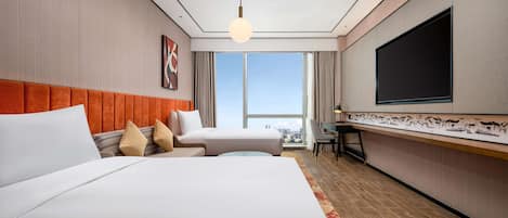 A hotel room with two beds, a large TV, a desk, and a city view.