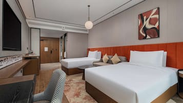 A hotel room with a large bed, a sofa, a desk, and a television.
