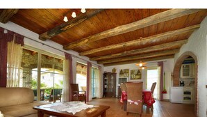A spacious living area with a wooden ceiling, a dining table with chairs, a sofa, and a kitchen area with a refrigerator and oven. - Villa Dany With View (Kastelir-Labinci)