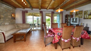 A cozy living room with a sofa, wooden coffee table, wicker chairs, a dining table with a red tablecloth, and a television. - Villa Dany With View (Kastelir-Labinci)