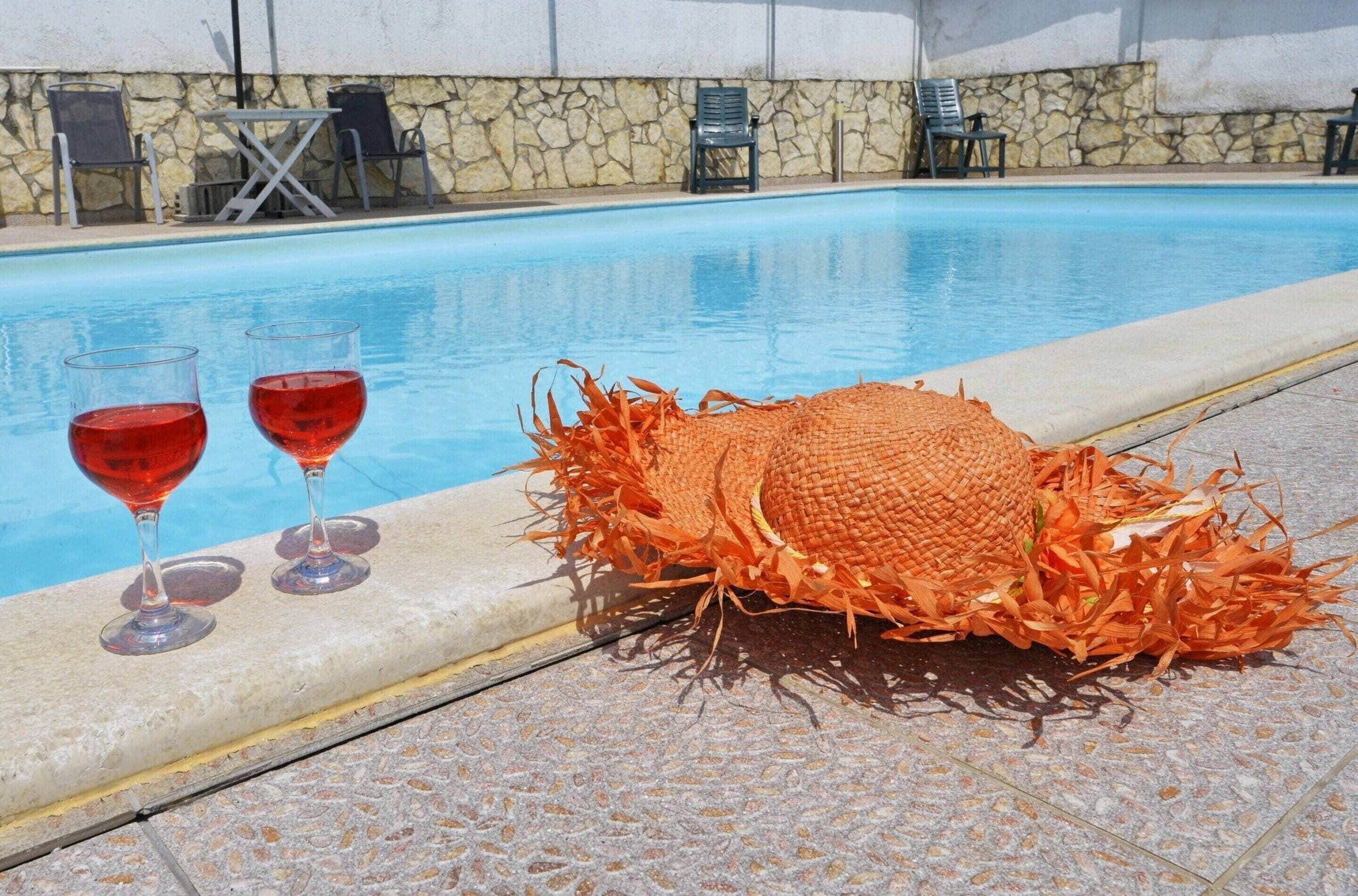 Un espace aménagé au bord de la piscine, avec un mur en pierre, des chaises longues et une décoration représentant un crabe, près du bord de la piscine.