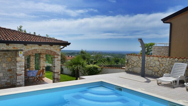 A swimming pool with a stone patio, a covered seating area, and a view of the landscape. - Villa Dany With View (Kastelir-Labinci)