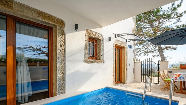 A swimming pool with a wooden deck, a table with chairs, and a view of the surrounding landscape. - Beautiful Villa in Nature (Groznjan)