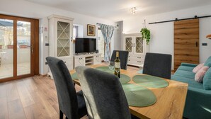 A modern living room with a dining area, a TV, and a sliding wooden door. - Beautiful Villa in Nature (Groznjan)