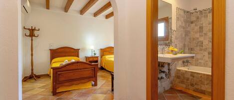Camera da letto con due letti, pavimento in legno e bagno con vasca e doccia.
