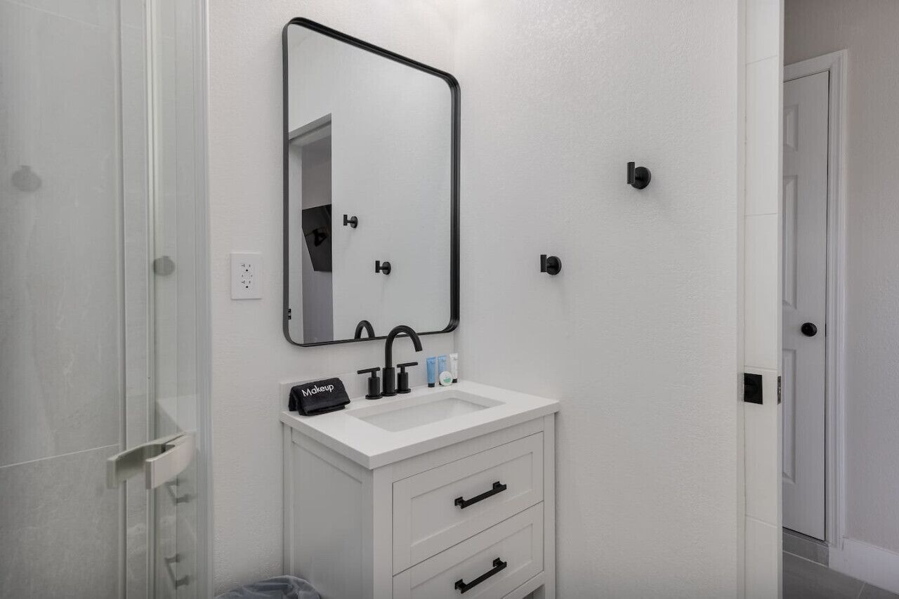 A bathroom with a white sink, a mirror, and a makeup station.