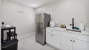 Een moderne keuken met witte kasten, een roestvrijstalen koelkast, een koffiezetapparaat en een spoelbak.