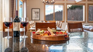 Un'area pranzo con un tavolo in legno apparecchiato per un pasto, una bottiglia di vino e calici su un piano di lavoro in granito.