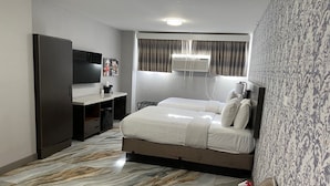 Une chambre d’hôtel équipée d’un lit, d’un bureau, d’une armoire, d’une télévision et d’une salle de bain avec douche.