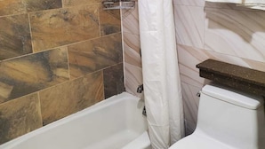 Une salle de bain avec une baignoire, des toilettes et un rideau de douche.