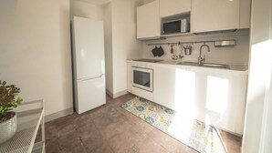 Eine kleine Küche mit weißen Schränken, einem Backofen, einer Mikrowelle und einem Spülbecken.