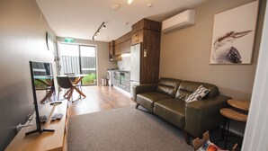 A modern living area with a sofa, a dining table, and a kitchen in the background.