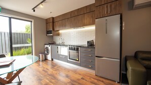 A modern kitchen with wooden cabinets, stainless steel appliances, and a glass dining table.
