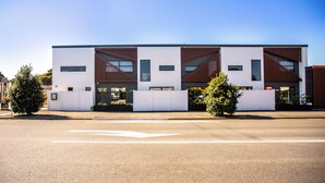 A modern building with a flat roof, large windows, and a gated entrance.