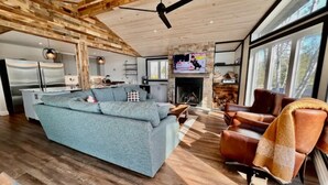 Un salon moderne avec un grand canapé d’angle, une cheminée et un mur en pierre.