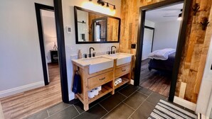 Une salle de bain moderne avec un mur d’accent en bois, un meuble-lavabo à deux vasques et un grand miroir.