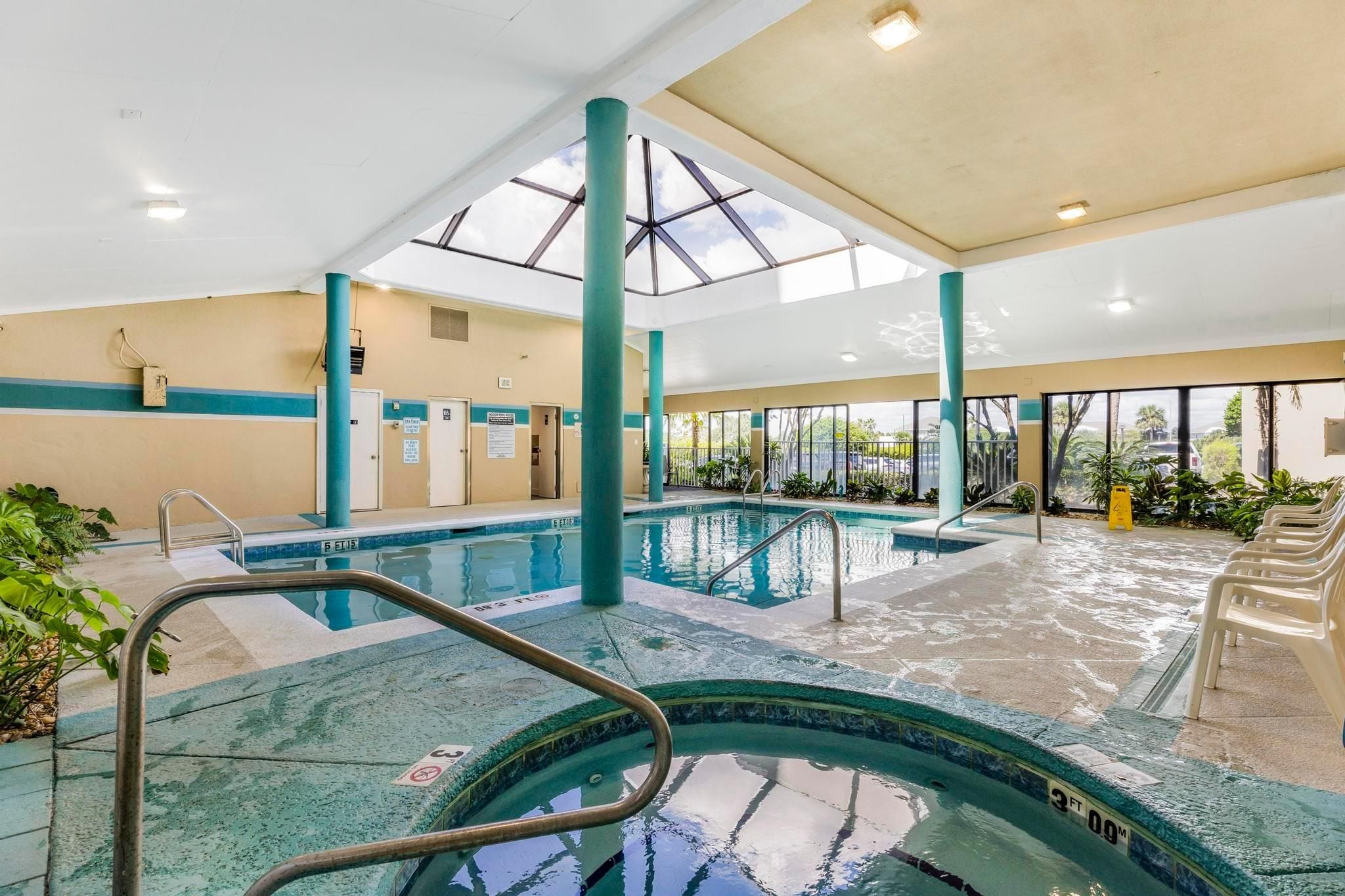 An indoor swimming pool with clear water, a diving board, and a sunroof.
