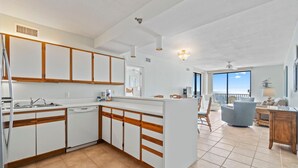 A modern kitchen with white cabinets and wooden accents, a built-in dishwasher, and a large island. - Romar Place 903 (Orange Beach)