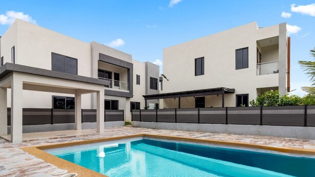 A modern residential building with a swimming pool, covered patio, and a view of the sky. - Coastal Escape Tower Isle Beach Nearby (Tower Isle)