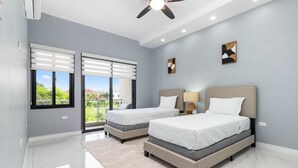 A modern bedroom with two beds, a balcony, and a ceiling fan. - Coastal Escape Tower Isle Beach Nearby (Tower Isle)