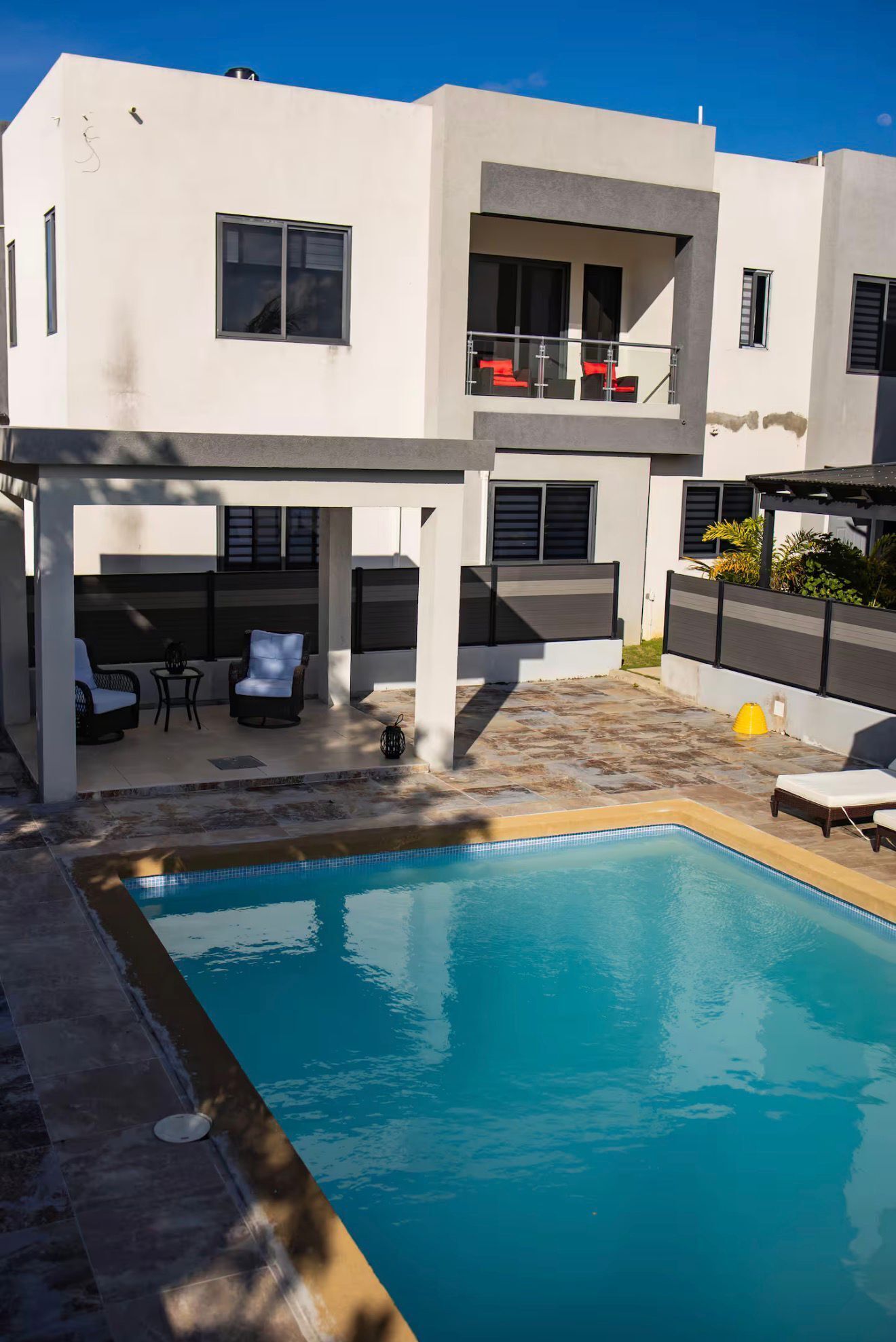 Un bâtiment moderne à deux étages doté d’une piscine, d’un espace extérieur aménagé et d’un balcon.