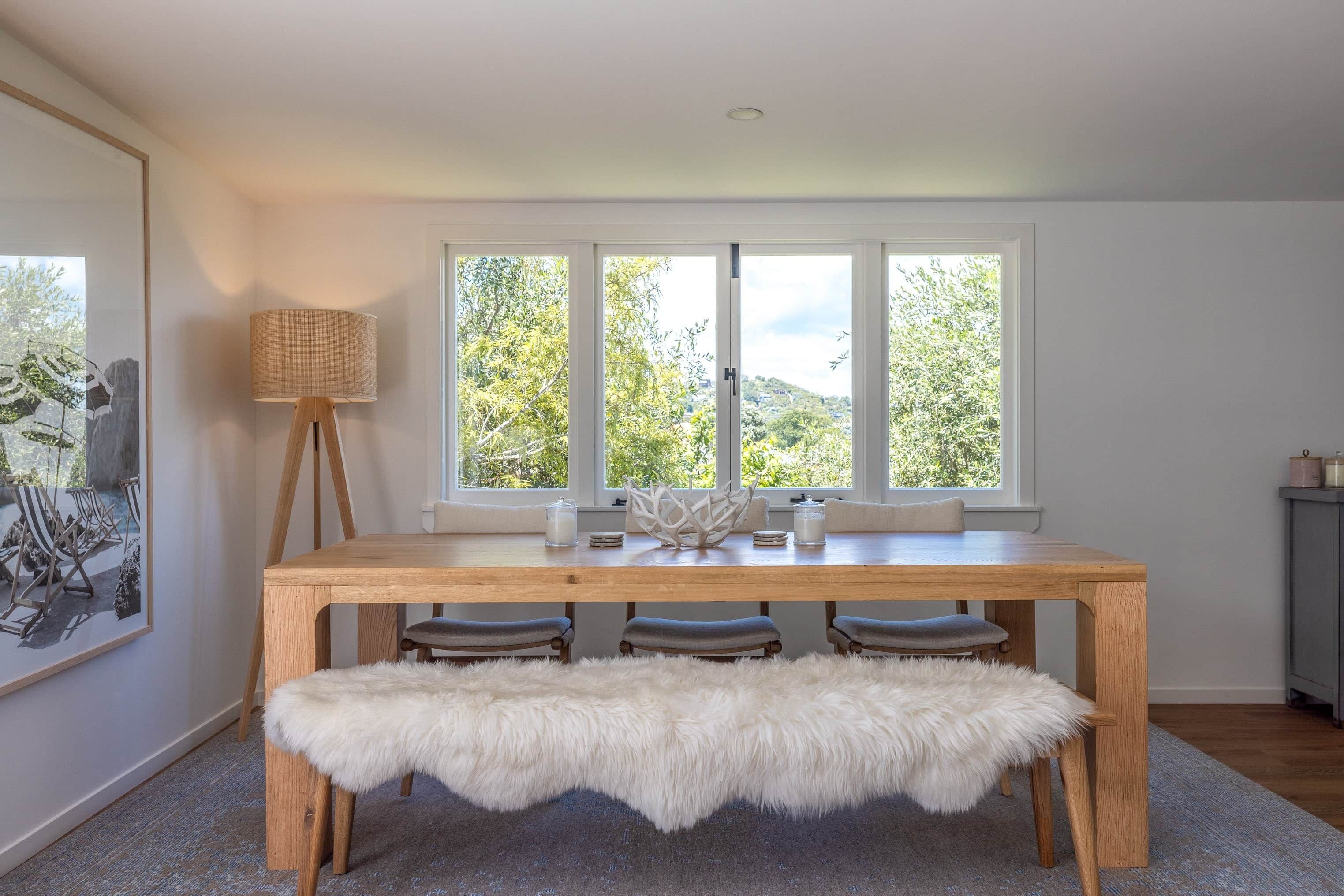 Un coin repas avec une table en bois, un banc et une lampe.