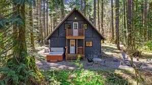 Eine Hütte mit Balkon, Whirlpool und Sitzgelegenheiten im Freien.