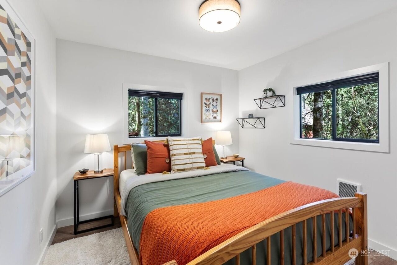 A bedroom with a bed, two bedside tables, a nightstand, a window, and a wall-mounted shelf.