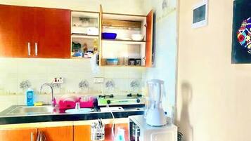 Una cucina con armadietti in legno, un lavello, un frullatore e una finestra sopra il bancone.