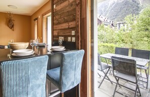 Un espace repas avec un mur en bois, un grand saladier, des verres à vin et une table entourée de chaises.