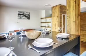 A modern kitchen with a central island, wooden cabinets, and a dining area with a bench.