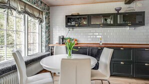 Una cocina con una mesa redonda, sillas blancas y armarios negros.