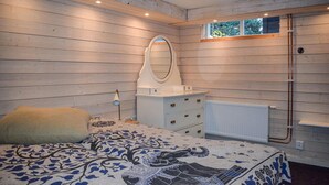 Un dormitorio con una cama, un aparador, un espejo y una ventana.