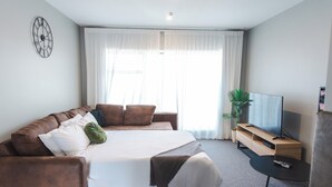 Ein modernes Hotelzimmer mit einem großen Bett, einem Fernseher und einem kleinen Tisch.