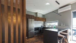 Eine moderne Küche mit Holzausstattung, Edelstahlgeräten und einer Bar mit Hockern.