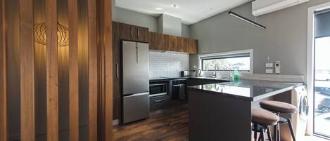 Una cocina moderna con armarios de madera, electrodomésticos de acero inoxidable y una barra con taburetes.