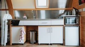 Una cocina compacta con un lavamanos de acero inoxidable, un microondas y un refrigerador pequeño.