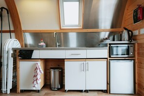 Une cuisine compacte équipée d’un évier en acier inoxydable, d’un four à micro-ondes et d’un petit réfrigérateur.