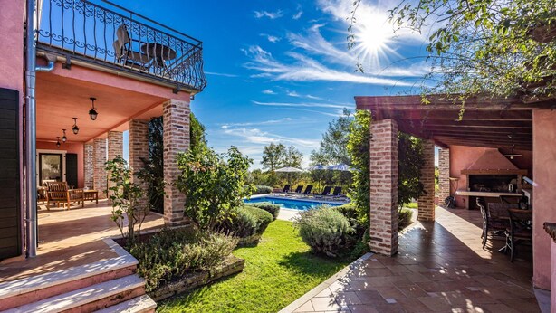 Amplio espacio al aire libre con piscina, un porche cubierto y fachada de ladrillo.